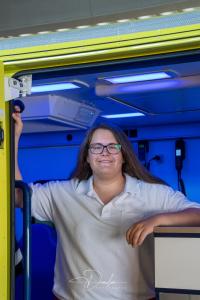 Person in weißem Hemd steht in einem blau beleuchteten Fahrzeug.
