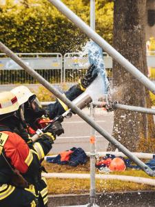 Feuerwehrleute in Schutzkleidung spritzen Wasser auf ein Metallgerüst bei einem Einsatz.