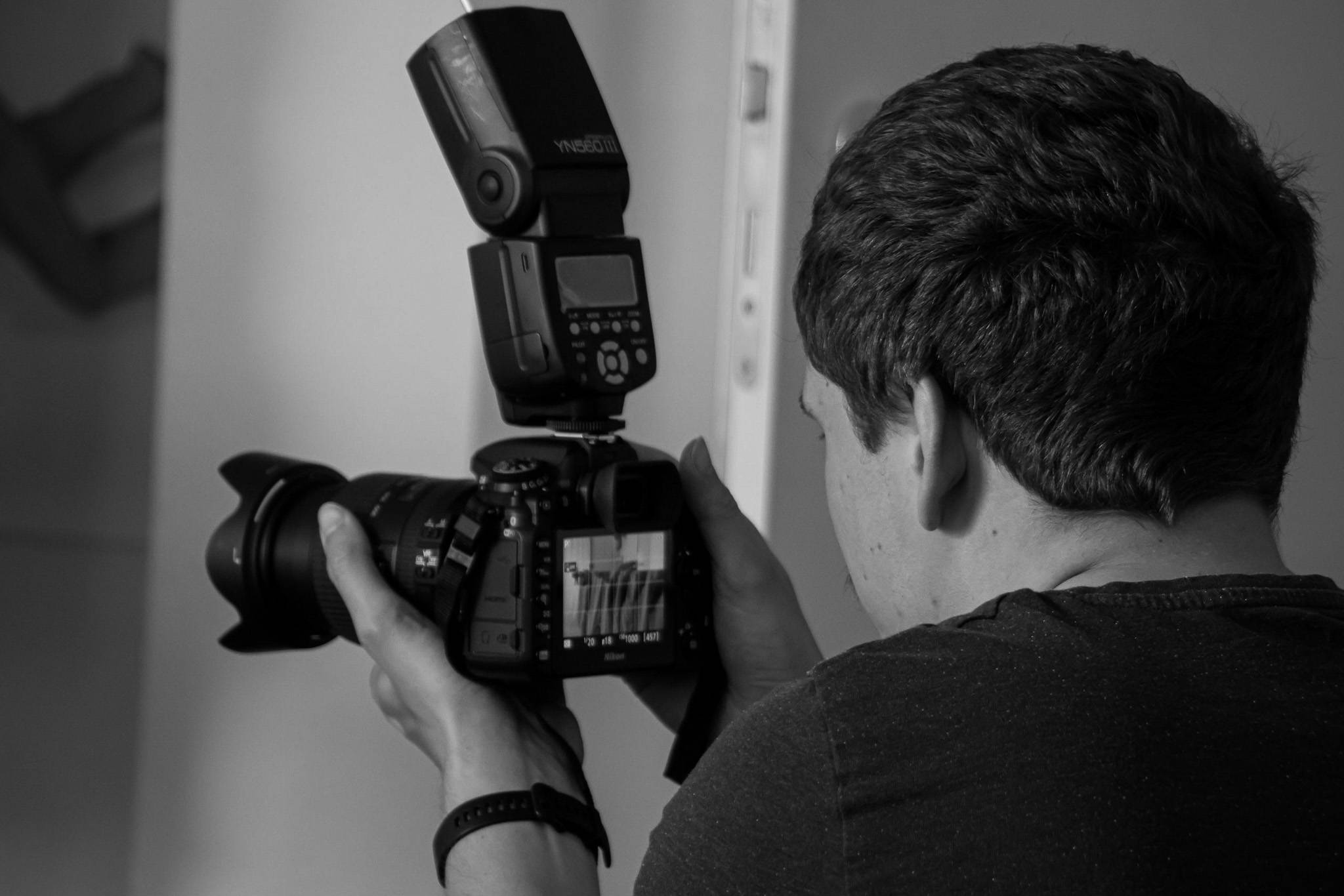 Eine Person hält eine Kamera mit Blitzgerät und fotografiert.