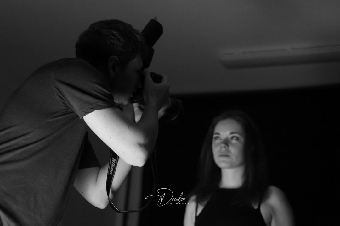 Fotografie 2 Ein Fotograf macht ein Porträtfoto von einer Frau in einem Studio.
