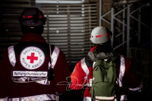 Zwei Personen in Rettungsausrüstung des Deutschen Roten Kreuzes in einem Gebäude.