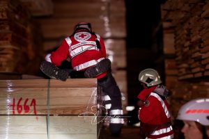 Personen in Rettungsausrüstung des Deutschen Roten Kreuzes arbeiten nachts in einem Holzlager.