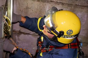 Rettungsarbeiter mit gelbem Helm und Schutzbrille bei der Arbeit in einem Schacht.