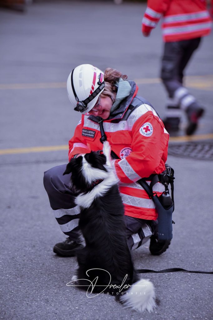 Event Fotografie 9 Rettungskräfte in Uniform knien vor einem schwarz-weißen Hund, der aufgerichtet steht.